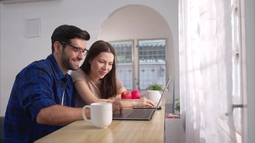Smiling Couple Using Laptop in Bright Home Kitchen