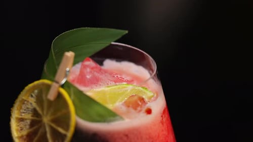 Refreshing Red Cocktail with Lime and Lemon Garnish