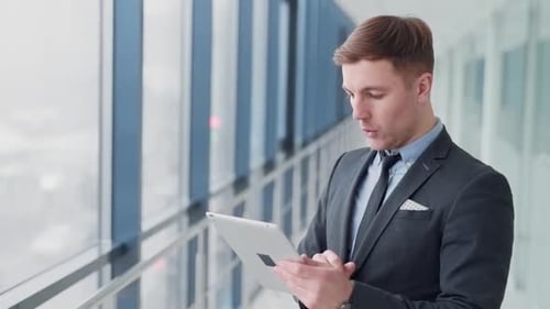Business man in the hallway of business center looking at tablet