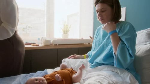 Young Mother, Baby and Unrecognizable Woman in Maternity Hospital