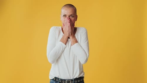 Surprised woman clapping her hands looking at camera isolated on yellow background in studio