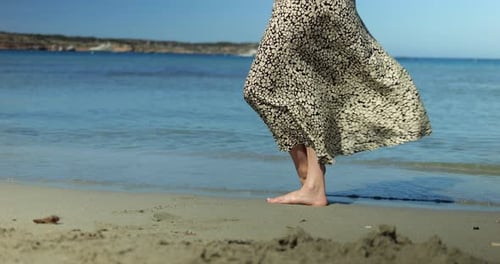 Unrecognizable Woman Bare Feet in Chiffon Dress Flutter in Breeze on Sea Shore