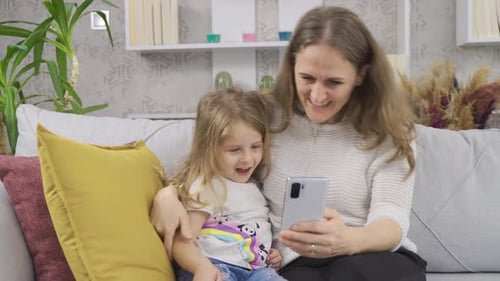 Mother and Daughter Using Mobile Phone at Home