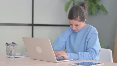 Woman Typing on Laptop Rubs Neck in Discomfort
