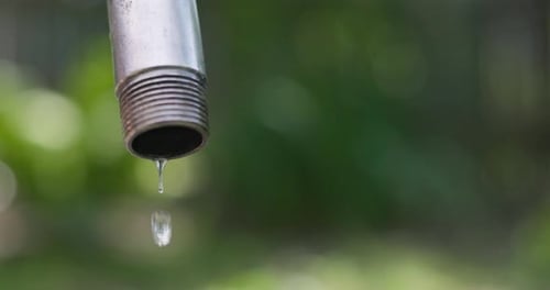 Water Drips From a Leaky Faucet with a Blurred Background Water Saving Concept