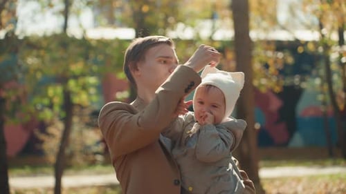 Young Father Holds Adorable Baby in Autumn Park