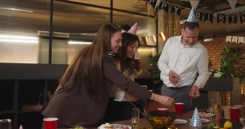Four Cheerful Friends of Colleagues in the Office in Business Clothes Remove Candles From the Cake