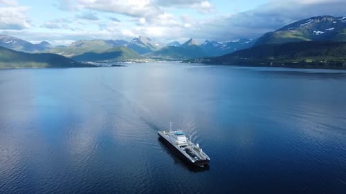 Overhead shot of a ferry crossing a fjord in Norway, beautiful snowy mountains in background