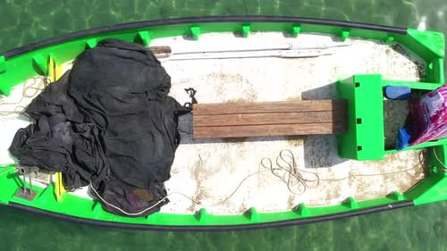 Kleines Fischerboot vor Anker in einer flachen Lagune, mit gepacktem Fischnetz an Bord
