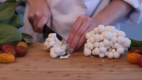 close up shot of chef cutting small white mushrooms for the dish