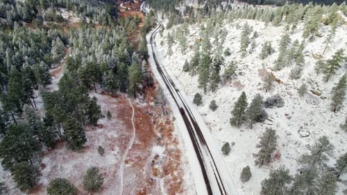 Drone Aerial View Of Cars Driving Through Winter Snow Covered Green Pine Tree Woodland Hills Near Ki