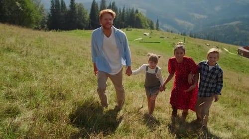 Friendly Family Walking on Mountain Slope Sunny Day. Happy Parents Holding Children
