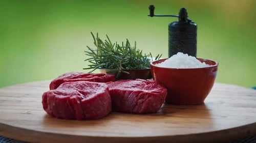 BBQ in the garden. Filet mignon rotates on the table with bbq seasonings, salt pepper, rosemary.