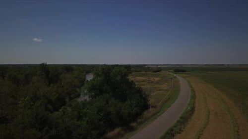 Aerial shot of a white car traveling through a lane in the countryside