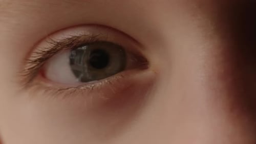 Close-up view of a child's blue eye opening and closing.