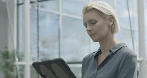 Femme d'affaires dans le hall du siège de l'Entreprise travaillant sur la technologie des tablettes numériques