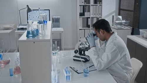 Scientist Uses Microscope in Bright Medical Laboratory