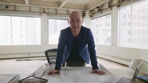 Confident architect reviews blueprint plans in bright modern canadian office
