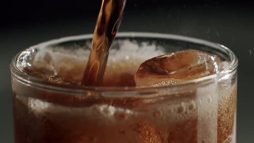 Soda Pouring into Glass with Ice and Bubbles