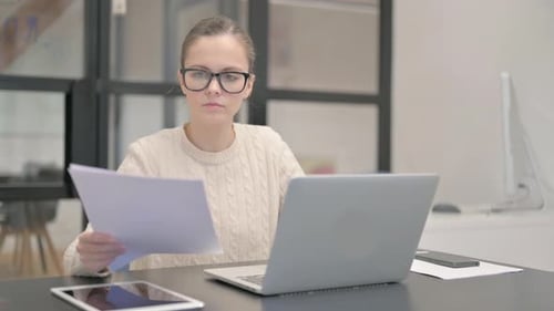 Woman Reviews Documents in Modern Office Environment