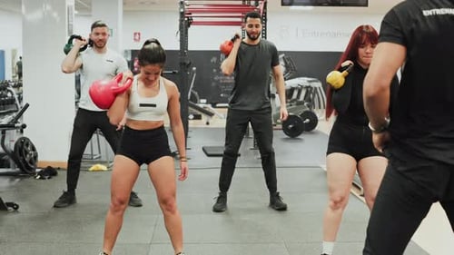 Group of People Training with Kettlebells and a Coach in a Gym