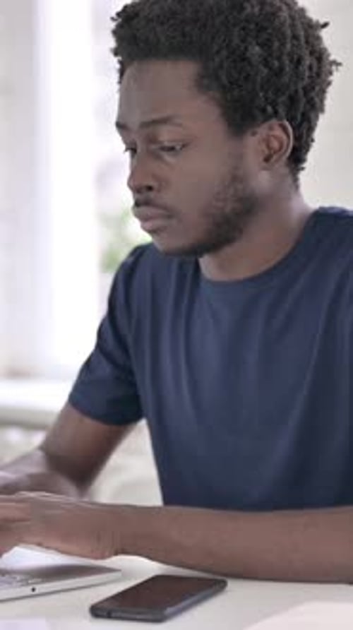Smiling Man Works on Laptop in Bright Room