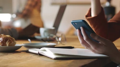 Woman hand, coffee shop and phone with notebook for communication, student research