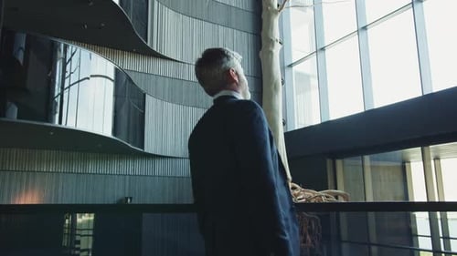 Vue arrière d'un homme d'affaires en costume regardant à distance le portrait d'un homme d'âge moyen riche et attentionné