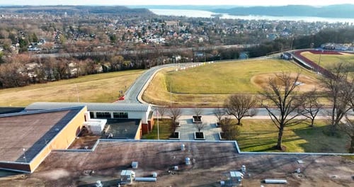 Bâtiment scolaire et mât de drapeau avec une ville au bord de la rivière dans la vallée. Un retrait aérien dévoile la salle de classe