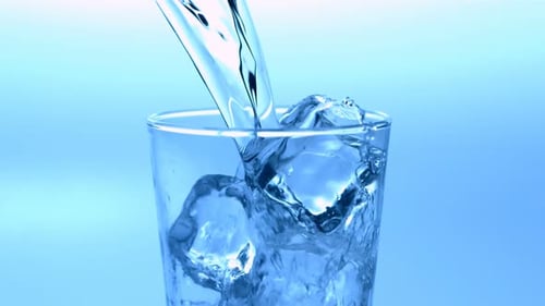Water Pouring into Glass with Ice Cubes