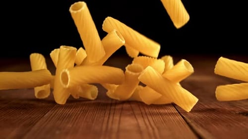 Rigatoni Pasta Falling on Wooden Table in Studio