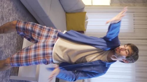 Vertical Video of The funny guy is trying to dance at home and it's fun for him.