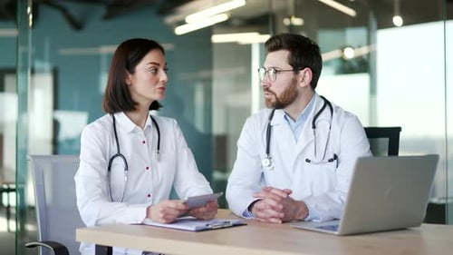 A team of two doctors having a professional discussion in a office with a tablet. Female and male