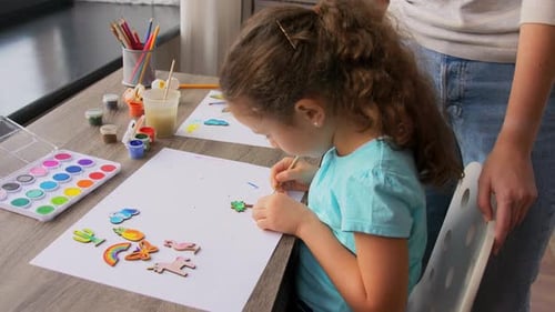 Child Paints Wood Cutout with Adult Supervision at Home