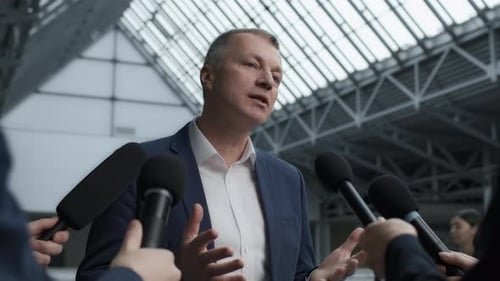 Successful entrepreneur interviewed at corporate press conference in modern building