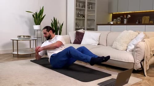 Hombre atlético de mediana edad haciendo ejercicio deportivo en línea en la computadora portátil en casa