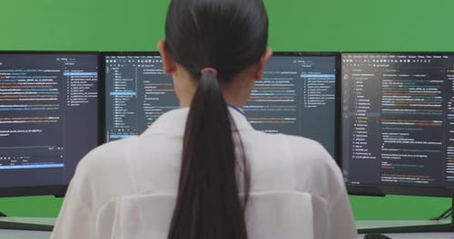 Asian Woman Developer Using Computer To Write Code With Multiple Screens In Green Screen Studio