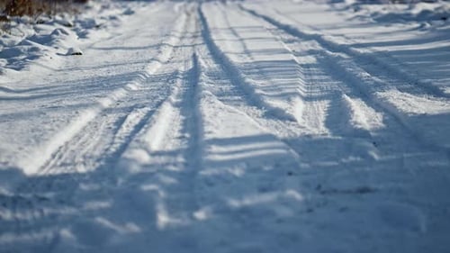 Frozen Snowy Road with Wheel Marks Sunny Winter Day Close Up. Snow-Covered