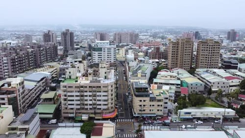 A dense cityscape with buildings and streets on overcast day, aerial view