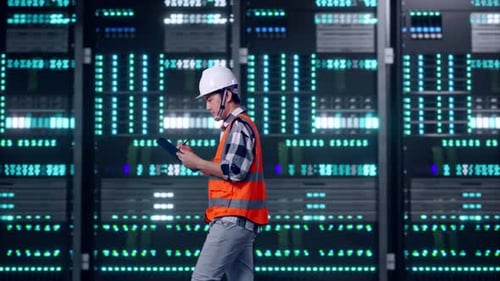 Asian Male Taking Note on Tablet While Walking in Data Center