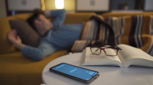 Man Relaxing on Couch with Phone and Book