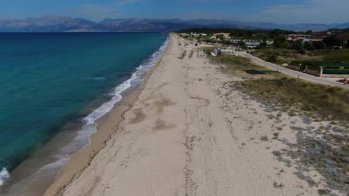 Aerial Drone Flies Along Wide Sandy Beach with Sunbeds, Umbrellas, and Beach Bar. Turquoise Sea and