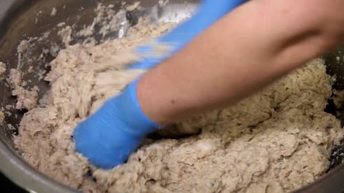 The Chef's Hands Mix Bread with Minced Fish and Egg in a Metal Bowl