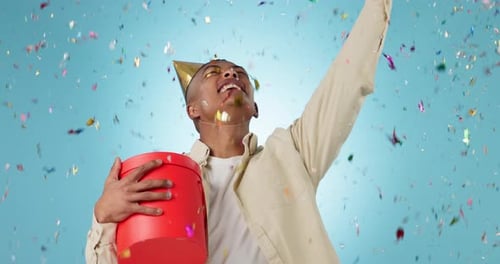 Birthday present, excited with man and confetti shower in studio, celebration