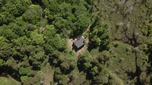 Bird's Eye View Of The Small Cabin House On The Midst Of The Green Forest. aerial