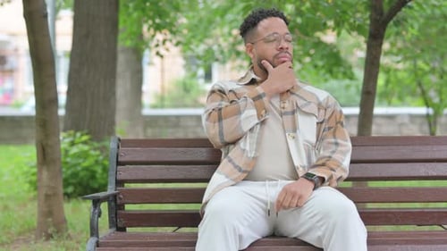 Thoughtful Man Sitting on Park Bench in City