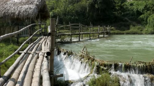Wooden bridge spans over the waterfall, blending harmoniously with nature