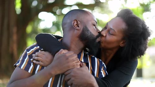 African couple kissing outside in sunny park. Beautiful Black couple love and affection embrace
