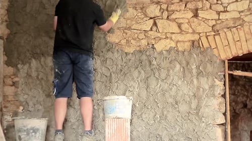Adult Applying Cement to Stone Wall Indoors