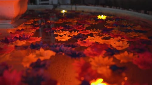 Colorful flowers and candles rotating in a pool under dim light from a different angle and sequince.